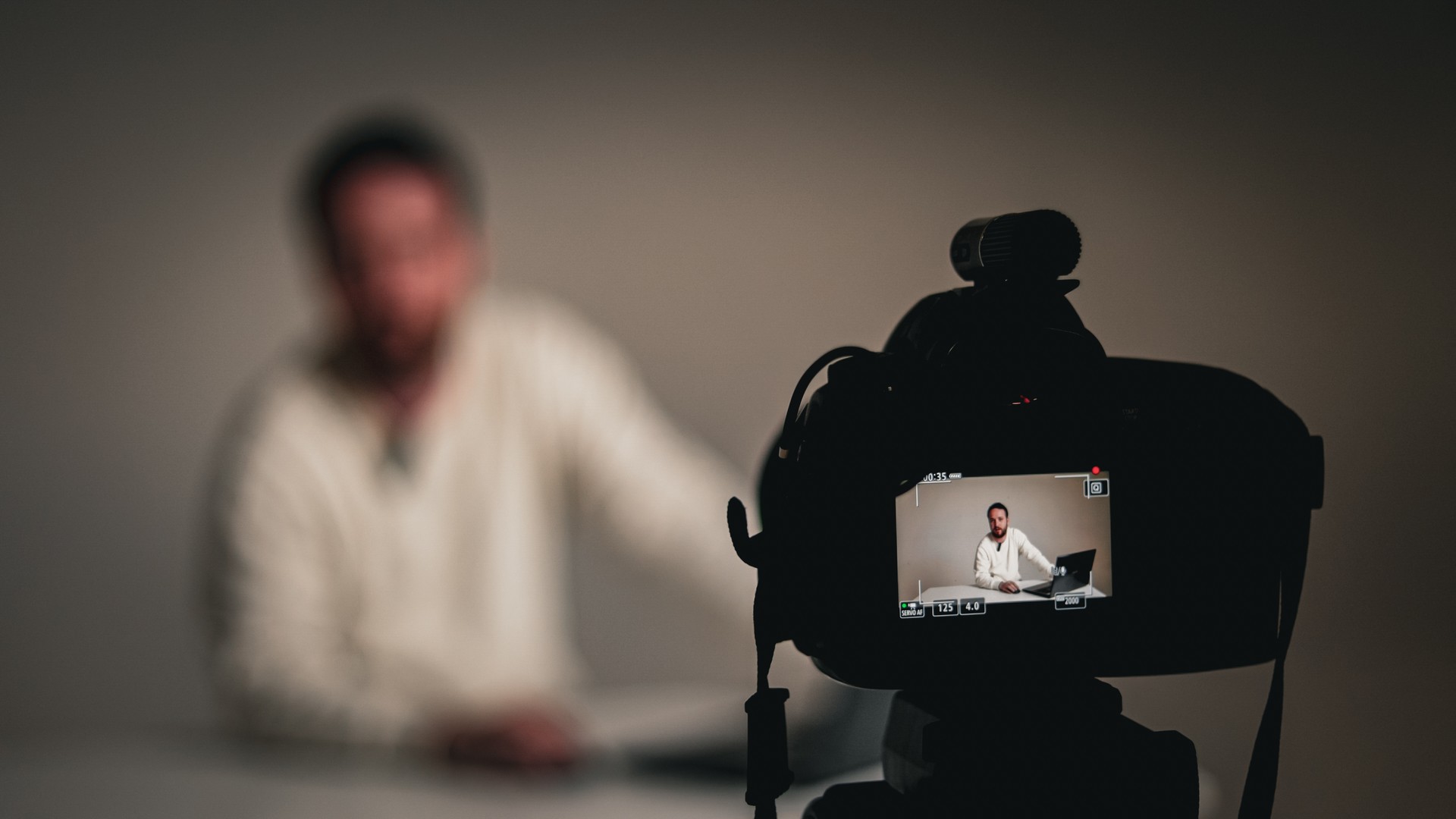 Young man vlogger or blogger recording, Shooting training video to share on social media, Handsome announcer looking and talking at camera, Newscaster man narrating with lapel microphone in white studio, Talking to camera while broadcasting live, Youtuber